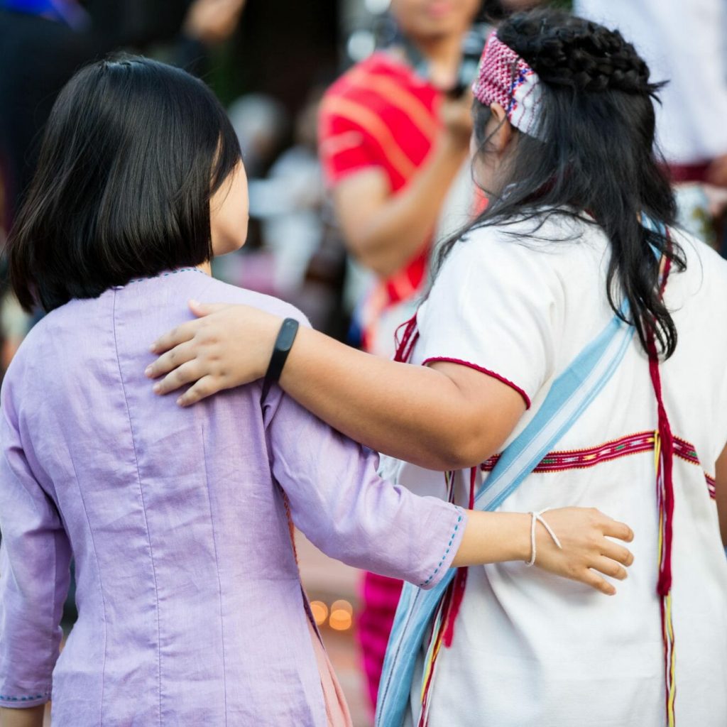 people with arms around each other shown from behind