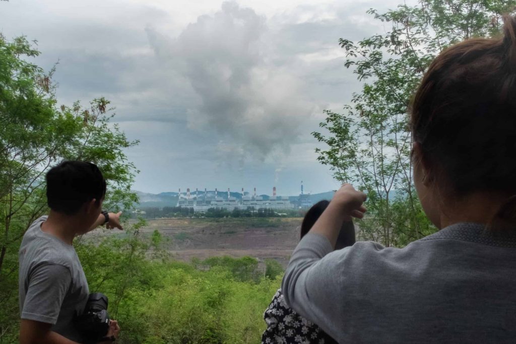 Community members from Nan look out at the Mae Moh open-pit lignite coal mine and power plant.