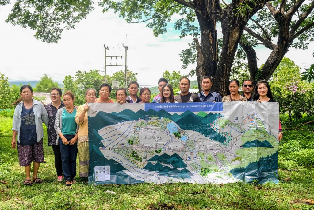Members of the Mae Moh and Nan communities pose with a map of one of the Nan communities, showing crops, rivers and watersheds.