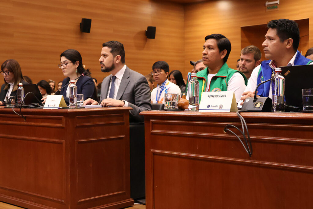 People in a courtroom at tables facing the judge