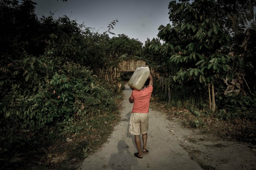 A villager brings water from the riverbank to his house.