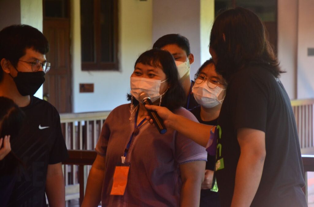person in mask at front of line speaking into a microphone